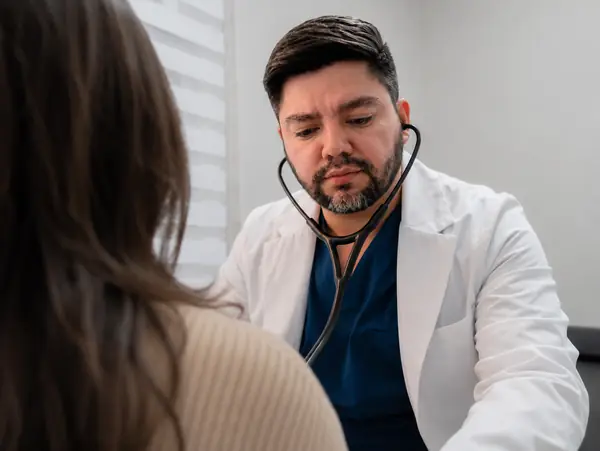 Dr. Contreras Reyes realizando auscultación cardíaca con estetoscopio a una paciente en Providencia